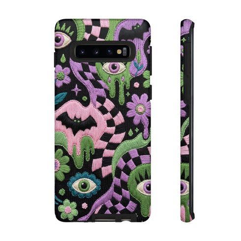 Dual layer phone case in matte or glossy with a 2D print that mimics thick crochet and yarn embroidery. Black bats, pink and green dripping slime, all-seeing eyes with lashes, purple and green daisies, and twisting pink and black checkered worms scatter across a black knit-look background. Smooth printed surface with no raised threads, open ports, and camera cutout. Pastel goth, creepy cute, whimsigoth, spooky maximalist phone accessory and gift.