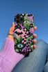 Dual layer phone case in matte or glossy with a 2D print that mimics thick crochet and yarn embroidery. Black bats, pink and green dripping slime, all-seeing eyes with lashes, purple and green daisies, and twisting pink and black checkered worms scatter across a black knit-look background. Smooth printed surface with no raised threads, open ports, and camera cutout. Pastel goth, creepy cute, whimsigoth, spooky maximalist phone accessory and gift.