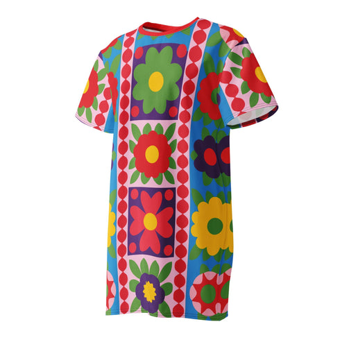Short sleeve crew neck t-shirt dress in a relaxed, oversized straight cut, made of 100% polyester with a soft matte finish. An edge-to-edge all-over print shows 70s mod flowers in red, green, yellow, and purple set inside quilt-style patchwork panels of hot pink, royal blue, and lavender, divided by vertical stripes of red and pink polka dots. Retro 70s hippie, patchwork quilt, dopamine dressing maximalist alt fashion.