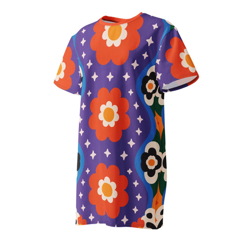 Short sleeve crew neck t-shirt dress in a relaxed, oversized straight cut, made of 100% polyester with a soft matte finish. An edge-to-edge all-over print on a medium purple background shows vertically stacked daisies with orange petals and yellow centers, scattered white four-point stars, and blue and green wavy side borders filled with small black and white daisies. Retro 70s floral, groovy maximalist alt fashion.