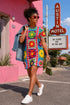Short sleeve crew neck t-shirt dress in a relaxed, oversized straight cut, made of 100% polyester with a soft matte finish. An edge-to-edge all-over print shows 70s mod flowers in red, green, yellow, and purple set inside quilt-style patchwork panels of hot pink, royal blue, and lavender, divided by vertical stripes of red and pink polka dots. Retro 70s hippie, patchwork quilt, dopamine dressing maximalist alt fashion.