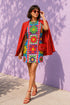 Short sleeve crew neck t-shirt dress in a relaxed, oversized straight cut, made of 100% polyester with a soft matte finish. An edge-to-edge all-over print shows 70s mod flowers in red, green, yellow, and purple set inside quilt-style patchwork panels of hot pink, royal blue, and lavender, divided by vertical stripes of red and pink polka dots. Retro 70s hippie, patchwork quilt, dopamine dressing maximalist alt fashion.
