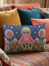 Rectangular 20 by 12 inch lumbar pillow cover printed to look like thick crewel embroidery on a deep royal blue night sky dotted with orange, yellow, and white stars. A silver, pink, and yellow flying saucer beams a bright pink cone of light onto a white cow with green spots standing in green grass with pine trees and red and pink flowers. Smooth flat 2D print, not raised stitching. Maximalist sci-fi decor for a bed, sofa, or reading nook.