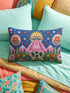 Rectangular 20 by 12 inch lumbar pillow cover printed to look like thick crewel embroidery on a deep royal blue night sky dotted with orange, yellow, and white stars. A silver, pink, and yellow flying saucer beams a bright pink cone of light onto a white cow with green spots standing in green grass with pine trees and red and pink flowers. Smooth flat 2D print, not raised stitching. Maximalist sci-fi decor for a bed, sofa, or reading nook.
