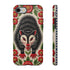 Dual layer matte phone case with a 2D print that mimics thick crewel embroidery. An angry black possum with a white face, bared sharp teeth, and bright red eyes and claws sits at the center on a cream background, framed by a symmetrical border of red folk art daisies with yellow centers and green leaves. Smooth printed surface with no raised threads, open ports, and a precise camera cutout. Goblincore, creepy cute, maximalist phone accessory.
