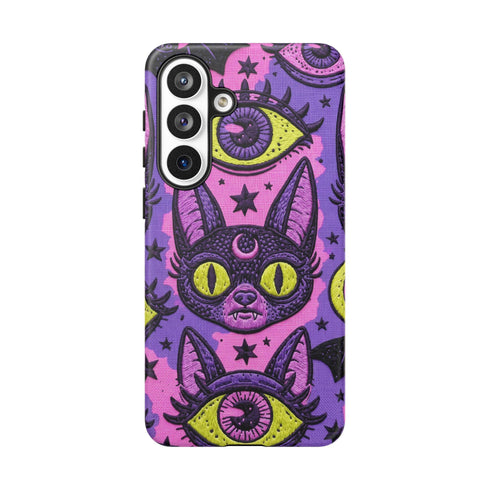 Dual layer matte phone case with a 2D print that mimics raised embroidery. Dark purple vampire bat cat heads with tall pointed ears, glowing chartreuse eyes, tiny fangs, and a pink crescent moon on the forehead repeat across a mottled purple and hot pink background, scattered with large chartreuse evil eyes with purple irises and small dark stars. Smooth printed surface with no raised threads, open ports, and camera cutout. Pastel goth, whimsigoth, creepy cute phone accessory.