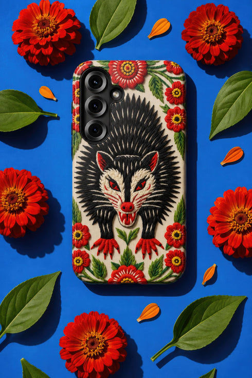 Dual layer matte phone case with a 2D print that mimics thick crewel embroidery. An angry black possum with a white face, bared sharp teeth, and bright red eyes and claws sits at the center on a cream background, framed by a symmetrical border of red folk art daisies with yellow centers and green leaves. Smooth printed surface with no raised threads, open ports, and a precise camera cutout. Goblincore, creepy cute, maximalist phone accessory.