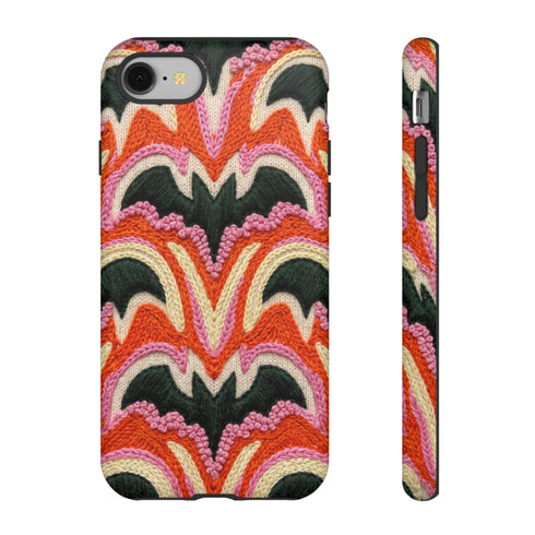 Dual layer matte phone case with a 2D print that mimics thick, heavy crochet yarn. Rows of stacked black bats repeat across a vibrant rust-orange background, accented with bright pink faux yarn bobbles and framed by cream arched lines. Smooth printed surface with no raised threads, open ports, and a precise camera cutout. Pastel goth, creepy cute, Summerween and Halloween phone accessory with a cozy handmade look.