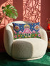 Rectangular 20 by 12 inch lumbar pillow cover printed to look like thick crewel embroidery on a deep royal blue night sky dotted with orange, yellow, and white stars. A silver, pink, and yellow flying saucer beams a bright pink cone of light onto a white cow with green spots standing in green grass with pine trees and red and pink flowers. Smooth flat 2D print, not raised stitching. Maximalist sci-fi decor for a bed, sofa, or reading nook.