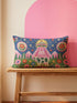 Rectangular 20 by 12 inch lumbar pillow cover printed to look like thick crewel embroidery on a deep royal blue night sky dotted with orange, yellow, and white stars. A silver, pink, and yellow flying saucer beams a bright pink cone of light onto a white cow with green spots standing in green grass with pine trees and red and pink flowers. Smooth flat 2D print, not raised stitching. Maximalist sci-fi decor for a bed, sofa, or reading nook.