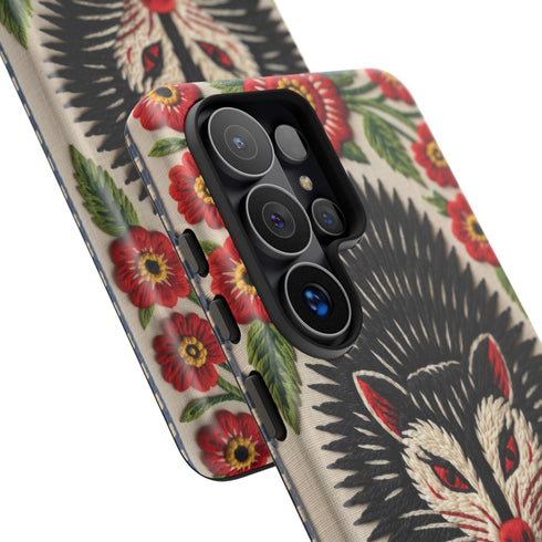 Dual layer matte phone case with a 2D print that mimics thick crewel embroidery. An angry black possum with a white face, bared sharp teeth, and bright red eyes and claws sits at the center on a cream background, framed by a symmetrical border of red folk art daisies with yellow centers and green leaves. Smooth printed surface with no raised threads, open ports, and a precise camera cutout. Goblincore, creepy cute, maximalist phone accessory.