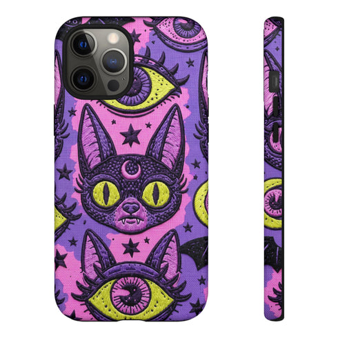 Dual layer matte phone case with a 2D print that mimics raised embroidery. Dark purple vampire bat cat heads with tall pointed ears, glowing chartreuse eyes, tiny fangs, and a pink crescent moon on the forehead repeat across a mottled purple and hot pink background, scattered with large chartreuse evil eyes with purple irises and small dark stars. Smooth printed surface with no raised threads, open ports, and camera cutout. Pastel goth, whimsigoth, creepy cute phone accessory.