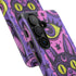 Dual layer matte phone case with a 2D print that mimics raised embroidery. Dark purple vampire bat cat heads with tall pointed ears, glowing chartreuse eyes, tiny fangs, and a pink crescent moon on the forehead repeat across a mottled purple and hot pink background, scattered with large chartreuse evil eyes with purple irises and small dark stars. Smooth printed surface with no raised threads, open ports, and camera cutout. Pastel goth, whimsigoth, creepy cute phone accessory.