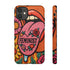 Dual layer matte phone case with a 2D print that mimics knit and embroidery texture. A retro open mouth with its tongue out sits over a pink heart stitched with the word FEMINIST in black letters, on an orange knit-look background filled with pink flowers, yellow sunflowers, red roses, purple and orange blooms, teal leaves, and a turquoise drip, all outlined in bold black. Smooth printed surface, open ports, camera cutout. Feminist maximalist phone accessory.