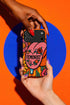 Dual layer matte phone case with a 2D print that mimics knit and embroidery texture. A retro open mouth with its tongue out sits over a pink heart stitched with the word FEMINIST in black letters, on an orange knit-look background filled with pink flowers, yellow sunflowers, red roses, purple and orange blooms, teal leaves, and a turquoise drip, all outlined in bold black. Smooth printed surface, open ports, camera cutout. Feminist maximalist phone accessory.