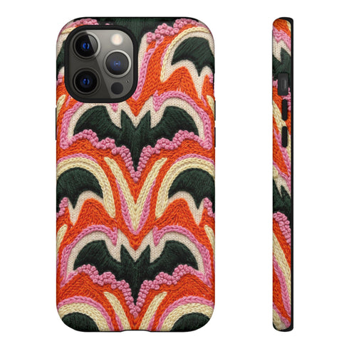 Dual layer matte phone case with a 2D print that mimics thick, heavy crochet yarn. Rows of stacked black bats repeat across a vibrant rust-orange background, accented with bright pink faux yarn bobbles and framed by cream arched lines. Smooth printed surface with no raised threads, open ports, and a precise camera cutout. Pastel goth, creepy cute, Summerween and Halloween phone accessory with a cozy handmade look.