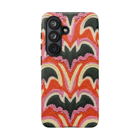 Dual layer matte phone case with a 2D print that mimics thick, heavy crochet yarn. Rows of stacked black bats repeat across a vibrant rust-orange background, accented with bright pink faux yarn bobbles and framed by cream arched lines. Smooth printed surface with no raised threads, open ports, and a precise camera cutout. Pastel goth, creepy cute, Summerween and Halloween phone accessory with a cozy handmade look.