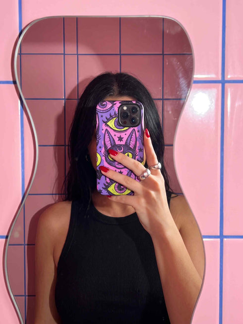 Dual layer matte phone case with a 2D print that mimics raised embroidery. Dark purple vampire bat cat heads with tall pointed ears, glowing chartreuse eyes, tiny fangs, and a pink crescent moon on the forehead repeat across a mottled purple and hot pink background, scattered with large chartreuse evil eyes with purple irises and small dark stars. Smooth printed surface with no raised threads, open ports, and camera cutout. Pastel goth, whimsigoth, creepy cute phone accessory.