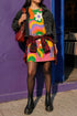 Short sleeve crew neck t-shirt dress in a relaxed, oversized straight cut, made of 100% polyester with a soft matte finish. An edge-to-edge all-over print shows pop-art daisies in cream, yellow, orange, and purple layered over wavy psychedelic stripes of hot pink, kelly green, orange, purple, and yellow. Retro 60s mod, flower power, psychedelic pop art, dopamine dressing maximalist alt fashion for festivals.