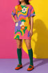Short sleeve crew neck t-shirt dress in a relaxed, oversized straight cut, made of 100% polyester with a soft matte finish. An edge-to-edge all-over print shows pop-art daisies in cream, yellow, orange, and purple layered over wavy psychedelic stripes of hot pink, kelly green, orange, purple, and yellow. Retro 60s mod, flower power, psychedelic pop art, dopamine dressing maximalist alt fashion for festivals.