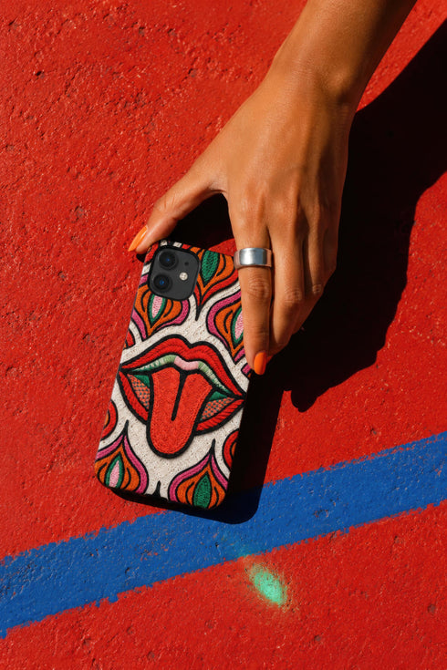 Dual layer matte phone case with a 2D print that mimics heavy crochet and thick knit yarn. A large open mouth with bright red lips and a red tongue sticking out sits at the center of a cream background, surrounded by mirrored teardrop and flame shapes in bright orange, dark green, and hot pink with black stitch-style outlines. Smooth printed surface with no raised threads, open ports, and camera cutout. Psychedelic 70s pop art phone accessory.