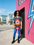 Short sleeve crew neck t-shirt dress in a relaxed, oversized straight cut, made of 100% polyester with a soft matte finish. An edge-to-edge all-over print on a true black background shows a large blue and white evil eye inside an orange wavy sunburst with a white jagged border, pink daisies with orange centers, white four-petal stars, and wavy blue and teal green leaves. Psychedelic whimsigoth, witchy celestial maximalist alt fashion.