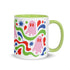 Glossy white ceramic 11 oz coffee mug with a lime green rim, inside, and handle and a full wraparound pastel goth print. Pink ghosts with paired red oval eyes and rounded scalloped lower edges float between wavy green and red ribbons. Blue starbursts, curved blue shapes, red teardrops, small colorful dots, and green diamond sparkles fill the white background. Creepy cute Halloween coffee mug with a playful, retro maximalist feel.