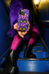 Dual layer matte phone case with a 2D print that mimics raised embroidery. Dark purple vampire bat cat heads with tall pointed ears, glowing chartreuse eyes, tiny fangs, and a pink crescent moon on the forehead repeat across a mottled purple and hot pink background, scattered with large chartreuse evil eyes with purple irises and small dark stars. Smooth printed surface with no raised threads, open ports, and camera cutout. Pastel goth, whimsigoth, creepy cute phone accessory.