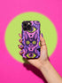Dual layer matte phone case with a 2D print that mimics raised embroidery. Dark purple vampire bat cat heads with tall pointed ears, glowing chartreuse eyes, tiny fangs, and a pink crescent moon on the forehead repeat across a mottled purple and hot pink background, scattered with large chartreuse evil eyes with purple irises and small dark stars. Smooth printed surface with no raised threads, open ports, and camera cutout. Pastel goth, whimsigoth, creepy cute phone accessory.