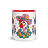 Glossy white ceramic coffee mug with a colored rim, inside, and handle and a full wraparound folk art print. Chickens wear pink cowboy hats with teal bands, yellow diamonds, flowers, and teardrop motifs. The birds have white heads, red combs and wattles, and layered pink, teal, and golden yellow feathers outlined in black. Pink and yellow flowers, teal leaves, and four-point starbursts fill the space between. Retro western kitchen decor.
