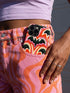 Dual layer matte phone case with a 2D print that mimics thick, heavy crochet yarn. Rows of stacked black bats repeat across a vibrant rust-orange background, accented with bright pink faux yarn bobbles and framed by cream arched lines. Smooth printed surface with no raised threads, open ports, and a precise camera cutout. Pastel goth, creepy cute, Summerween and Halloween phone accessory with a cozy handmade look.