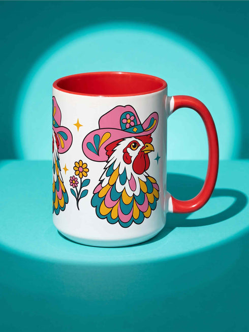 Glossy white ceramic coffee mug with a colored rim, inside, and handle and a full wraparound folk art print. Chickens wear pink cowboy hats with teal bands, yellow diamonds, flowers, and teardrop motifs. The birds have white heads, red combs and wattles, and layered pink, teal, and golden yellow feathers outlined in black. Pink and yellow flowers, teal leaves, and four-point starbursts fill the space between. Retro western kitchen decor.