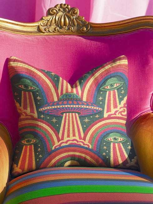 Square 70s psychedelic throw pillow cover printed to look like textured embroidery on a dark, starry navy background. Retro flying saucers and stylized alien eyes repeat across the design above rainbow arches, with small yellow stars and beams of light. Smooth flat 2D print, not raised stitching. Trippy, groovy, retro space age maximalist decor for a sofa, dorm bed, or reading nook, made for sci-fi fans and alien lovers.