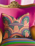 Square 70s psychedelic throw pillow cover printed to look like textured embroidery on a dark, starry navy background. Retro flying saucers and stylized alien eyes repeat across the design above rainbow arches, with small yellow stars and beams of light. Smooth flat 2D print, not raised stitching. Trippy, groovy, retro space age maximalist decor for a sofa, dorm bed, or reading nook, made for sci-fi fans and alien lovers.