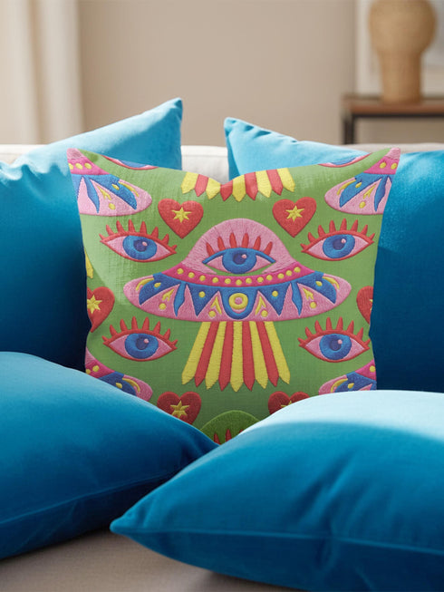 Square weirdcore throw pillow cover printed to look like textured crewel embroidery on a green background. A pink and blue flying saucer with one large blue eye at its center hovers among floating blue eyeballs and red hearts. Smooth flat 2D print, not raised stitching. Maximalist, trippy sci-fi dopamine decor with quirky alien charm for a sofa, dorm bed, gaming chair, or reading nook, made for space lovers and sci-fi fans.