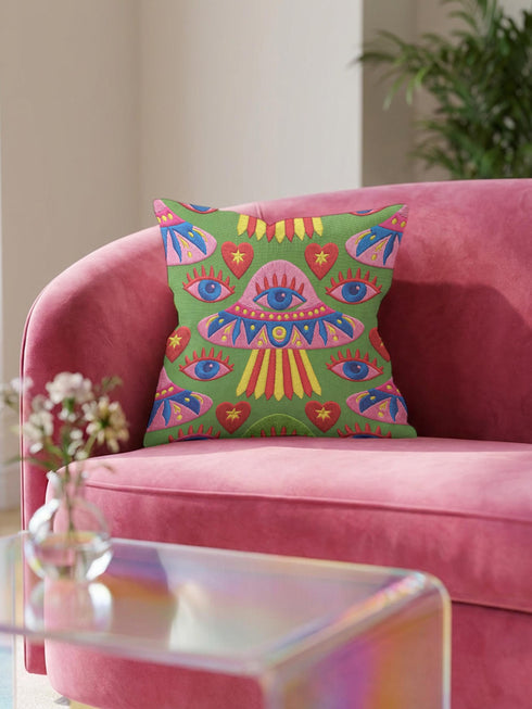 Square weirdcore throw pillow cover printed to look like textured crewel embroidery on a green background. A pink and blue flying saucer with one large blue eye at its center hovers among floating blue eyeballs and red hearts. Smooth flat 2D print, not raised stitching. Maximalist, trippy sci-fi dopamine decor with quirky alien charm for a sofa, dorm bed, gaming chair, or reading nook, made for space lovers and sci-fi fans.