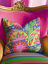 Square maximalist throw pillow cover printed to look like bold crewel embroidery on a solid royal blue background. Tacos with green, red, and brown fillings scatter across the design with bright green saguaro cacti, large pink and red starburst flowers, and small yellow stars. Smooth flat 2D print, not raised stitching. Colorful, quirky dopamine decor for a sofa, kitchen bench, or breakfast nook, made for taco lovers and foodies.