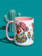 Glossy white ceramic coffee mug with a colored rim, inside, and handle and a full wraparound folk art print. Chickens wear pink cowboy hats with teal bands, yellow diamonds, flowers, and teardrop motifs. The birds have white heads, red combs and wattles, and layered pink, teal, and golden yellow feathers outlined in black. Pink and yellow flowers, teal leaves, and four-point starbursts fill the space between. Retro western kitchen decor.