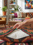 Square 70s psychedelic throw pillow cover printed to look like textured embroidery on a dark, starry navy background. Retro flying saucers and stylized alien eyes repeat across the design above rainbow arches, with small yellow stars and beams of light. Smooth flat 2D print, not raised stitching. Trippy, groovy, retro space age maximalist decor for a sofa, dorm bed, or reading nook, made for sci-fi fans and alien lovers.