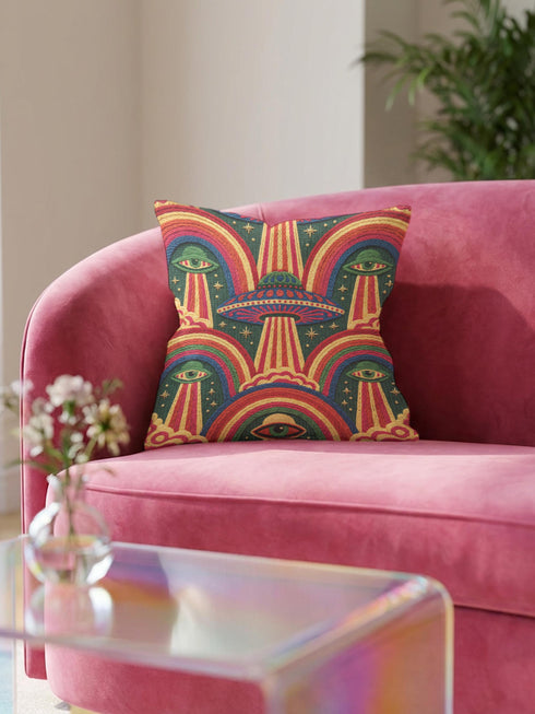 Square 70s psychedelic throw pillow cover printed to look like textured embroidery on a dark, starry navy background. Retro flying saucers and stylized alien eyes repeat across the design above rainbow arches, with small yellow stars and beams of light. Smooth flat 2D print, not raised stitching. Trippy, groovy, retro space age maximalist decor for a sofa, dorm bed, or reading nook, made for sci-fi fans and alien lovers.
