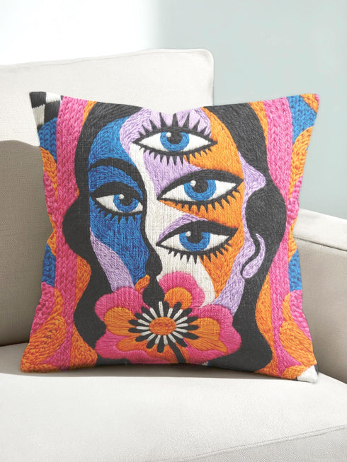 Square psychedelic throw pillow cover with a surreal weirdcore face printed to look like textured crewel embroidery. The face has a third eye and extra blue eyes, long dark hair, and a large pink and orange flower over the mouth, framed by radiating wavy stripes in hot pink, orange, and cobalt blue with black and white checkerboard corners. Smooth flat 2D print, not raised stitching. Maximalist 70s trippy decor for a sofa, armchair, or dorm bed.
