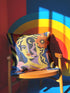 Square eclectic throw pillow cover with a surreal modern art portrait printed to look like textured crewel embroidery on a cobalt blue background. A yellow and purple half face with red lips holds a yellow crescent moon and a pink and purple staircase inside its dark silhouette, with a large orange flower in wavy yellow hair and abstract pink and yellow shapes around it. Smooth flat 2D print, not raised stitching. Maximalist art decor for a sofa, studio chair, or dorm.