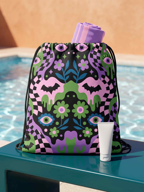 Drawstring backpack measuring 15 by 17 inches, made of 100% polyester with narrow shoulder straps and a drawstring closure. A symmetrical pastel goth print of bats, stylized eyes, flowers, and stars in a soft pastel palette sits on a black base, framed by purple and green checkerboard bands. Creepy cute, whimsigoth, kawaii goth style bag made for the gym, concerts, festivals, travel, school, and everyday carry.