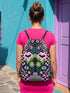 Drawstring backpack measuring 15 by 17 inches, made of 100% polyester with narrow shoulder straps and a drawstring closure. A symmetrical pastel goth print of bats, stylized eyes, flowers, and stars in a soft pastel palette sits on a black base, framed by purple and green checkerboard bands. Creepy cute, whimsigoth, kawaii goth style bag made for the gym, concerts, festivals, travel, school, and everyday carry.