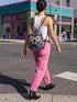 Drawstring backpack measuring 15 by 17 inches, made of 100% polyester with narrow shoulder straps and a drawstring closure. A symmetrical pastel goth print of bats, stylized eyes, flowers, and stars in a soft pastel palette sits on a black base, framed by purple and green checkerboard bands. Creepy cute, whimsigoth, kawaii goth style bag made for the gym, concerts, festivals, travel, school, and everyday carry.