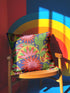 Square maximalist throw pillow cover printed to look like bold crewel embroidery on a solid royal blue background. Tacos with green, red, and brown fillings scatter across the design with bright green saguaro cacti, large pink and red starburst flowers, and small yellow stars. Smooth flat 2D print, not raised stitching. Colorful, quirky dopamine decor for a sofa, kitchen bench, or breakfast nook, made for taco lovers and foodies.