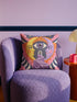 Square celestial throw pillow cover printed to look like heavy satin-stitch embroidery. A glowing yellow crescent sun and a lavender purple moon face a cosmic third eye, above a winding purple staircase that climbs to a starry archway framed by pink clouds and rayed sunbursts. Smooth flat 2D print, not raised stitching. Mystical, witchy, boho maximalist decor for a sofa, bed, reading nook, or altar corner, made for astrology lovers and tarot readers.