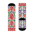 Pair of crew length socks with an all-over folk art print on a cream background. Red anatomical hearts stack vertically between symmetrical floral sprays with fine cream vessel lines, curling green stems and leaves, red flowers, purple tulip-shaped blooms, and small yellow accents. Red cuffs carry cream scrolling vines and small hearts above a scalloped border. Reinforced black heel and toe, striped ribbed cuff. Maximalist medical gift socks.