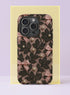 Front view of a dual layer tough phone case printed edge to edge with a coquette lace design. Black floral lace vines climb over a blush nude background, decorated with little pink satin bows and scattered cream pearls, all rendered as a realistic flat print. It looks like vintage lingerie and a jewelry box had a very pretty argument. Dark coquette lace and pearls phone accessory with open ports and a precise camera cutout.