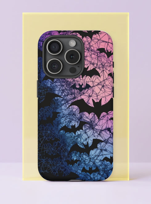 Front view of a dual layer tough phone case printed edge to edge with black bat silhouettes flying through a tangle of fine black web lines. The background fades from cotton candy pink at the top through lavender and periwinkle to deep navy blue at the bottom, like a gothic sunset. Delicate, spooky, and soft at the same time. Pastel goth bat phone accessory for Halloween every day, with open ports, dual layer protection, and a precise camera cutout.